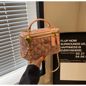 Detailed shot of pink tweed handbag featuring golden flower logo and metal chain strap