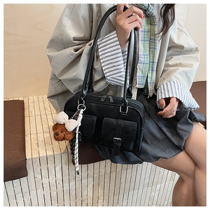Close-up of black retro Boston bag featuring front flap pockets and a cute bear charm