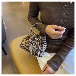 Detail of leopard print bucket bag featuring gold metal handle and chain tassel accents