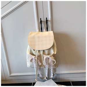 Detailed view of cream-colored backpack with plaid pattern flap and lace bow accents
