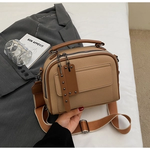Close-up of khaki leather handbag with litchi texture and adjustable wide fabric strap