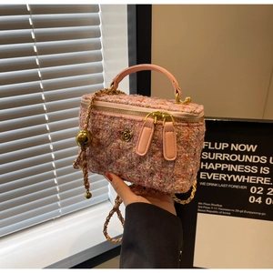 Detail of pink tweed texture and golden flower accent on a small crossbody chain bag