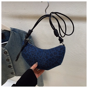 Detail of blue leopard denim crescent bag featuring quilted segments and knotted strap