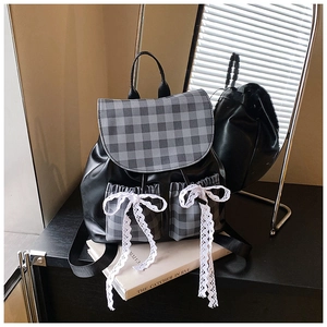 Detail of plaid flap backpack with decorative lace bows and dual front pockets
