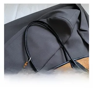 Detail of brown quilted suede tote bag with wooden bead tassel and black leather handles