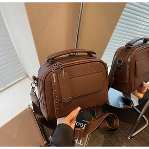 Detail view of brown lychee texture leather camera bag with wide strap and metallic studs