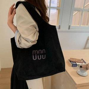 Detailed view of the large black suede tote bag featuring purple logo on the front