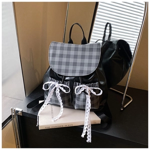 Detail of vintage plaid backpack featuring white lace bows and polished faux leather finish