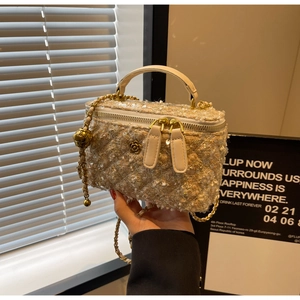 Detail of sequin fabric texture and gold flower emblem on a chic crossbody box bag