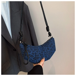 Detail of blue denim crescent bag with black leopard print and stylish knot strap