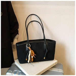 Detail of black quilted shoulder bag with bohemian beaded tassel and gold hardware