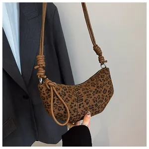 Detailed close-up of leopard print crescent bag with brown knotted shoulder strap