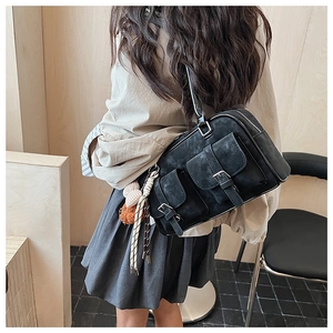 Detail of black Boston bag with utility pockets and plush puppy charm on model