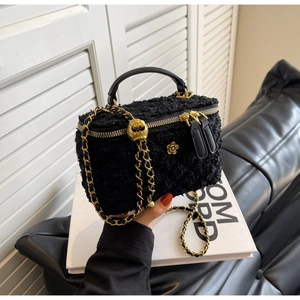Detailed shot of black tweed crossbody bag with golden chain and flower charms