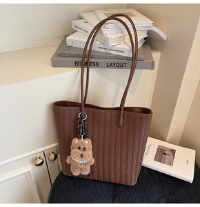 Detail of brown woven tote bag with V-pattern texture and cute plush bear charm