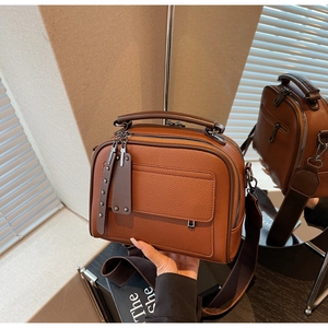Close-up of brown litchi pattern leather handbag with wide shoulder strap and zippers