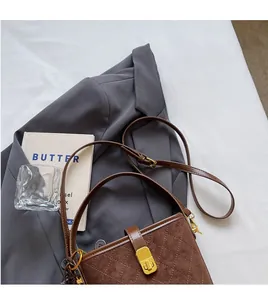 Macro shot of brown quilted bucket bag with golden buckle on elegant business attire
