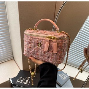 Detail of pink tweed texture and gold camellia buckle on a luxury mini vanity bag