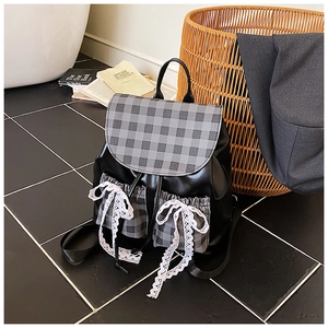 Detail of checkered patchwork backpack with large white lace bow and PU leather texture