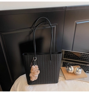 Dettaglio borsa shopper nera intrecciata con ciondolo a forma di orsetto in ufficio