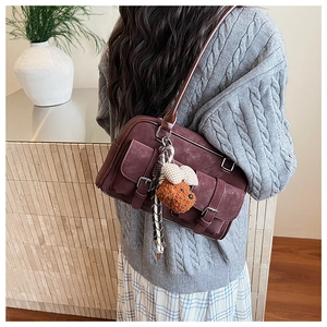 Detail of vintage burgundy shoulder bag with plush puppy charm and bow accessory