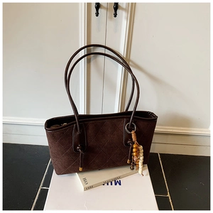 Detailed close-up of dark brown quilted tote bag with retro ethnic bead charm and golden zipper