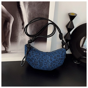 Detailed view of blue denim leopard print crescent bag with black knotted handle cord