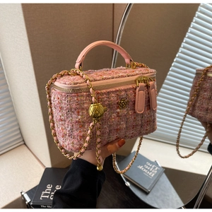 Detail of pink tweed box bag featuring golden flower hardware and chain strap