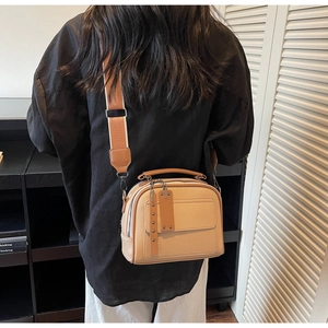 Detail of light brown lychee grain leather crossbody bag with wide woven strap
