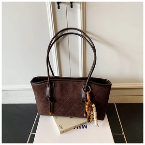 Detail of brown suede tote bag featuring diamond quilted stitching and ethnic bead charm