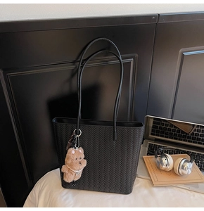 Dettaglio borsa shopper nera intrecciata con trama a V e ciondolo orsetto di peluche