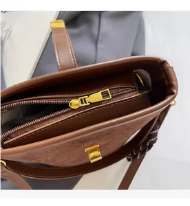 Close-up of brown bucket bag with gold zipper and textured leather contrast detail