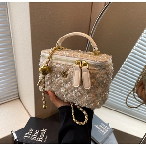 Detailed shot of champagne tweed box bag with gold camellia charm and ball chain strap
