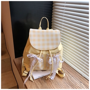 Close-up of yellow plaid backpack with white lace bows and checkered flap detail