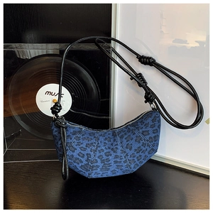 Close-up of blue denim leopard print dumpling bag with leather knot shoulder strap