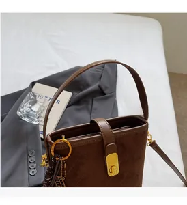 Close-up of dark brown quilted suede bucket bag with gold hardware and top handle