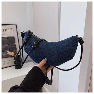 Detailed shot of blue leopard jacquard denim crescent bag with knotted rope shoulder strap