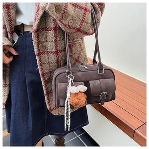 Detail of dark brown retro shoulder bag with dual pockets and plush puppy charm