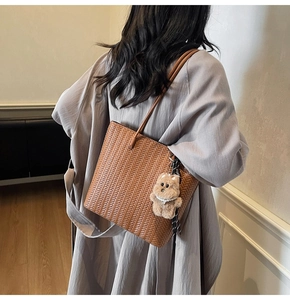 Dettaglio ravvicinato della borsa tote intrecciata marrone con trama a V e charm