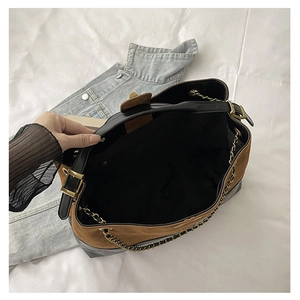 Detail view of large patchwork tote bag interior with gold chain and metal twist lock