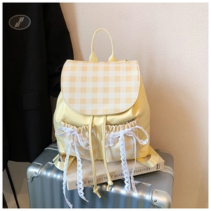 Detail view of yellow plaid backpack with lace bows on luggage for school