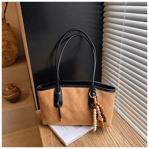 Detail of vintage brown quilted tote bag with matte texture and beaded tassel charm