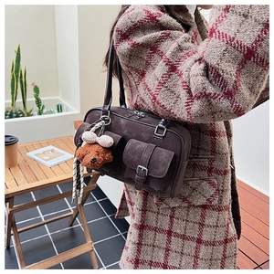 Detail of brown vintage Boston bag with leather straps and teddy bear charm accessory