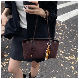 Detail of vintage brown quilted suede bucket bag with colorful beaded fringe accent