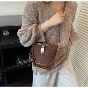 Close-up of brown bucket bag with diamond stitching and golden buckle closure