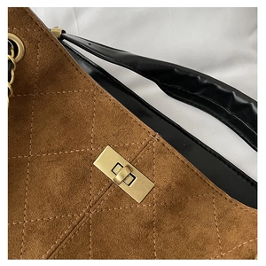 Close-up of brown suede shoulder bag featuring diamond quilting and gold metal twist lock