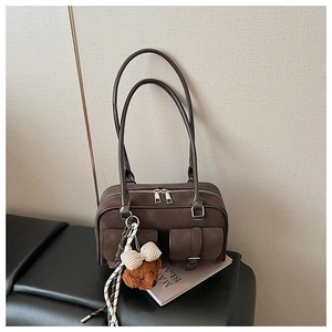 Detail of dark brown vintage handbag with dual front pockets and plush bear charm