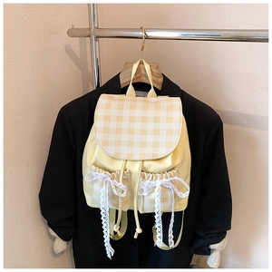 Detail showing checkered flap, drawstring pockets, and lace bows on a yellow backpack
