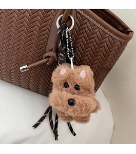Détail d'un charme chiot en peluche marron avec broderie sur un sac à main tissé