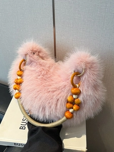 Sac à main rose en fausse fourrure avec poignée perlée sur livre blanc style chic